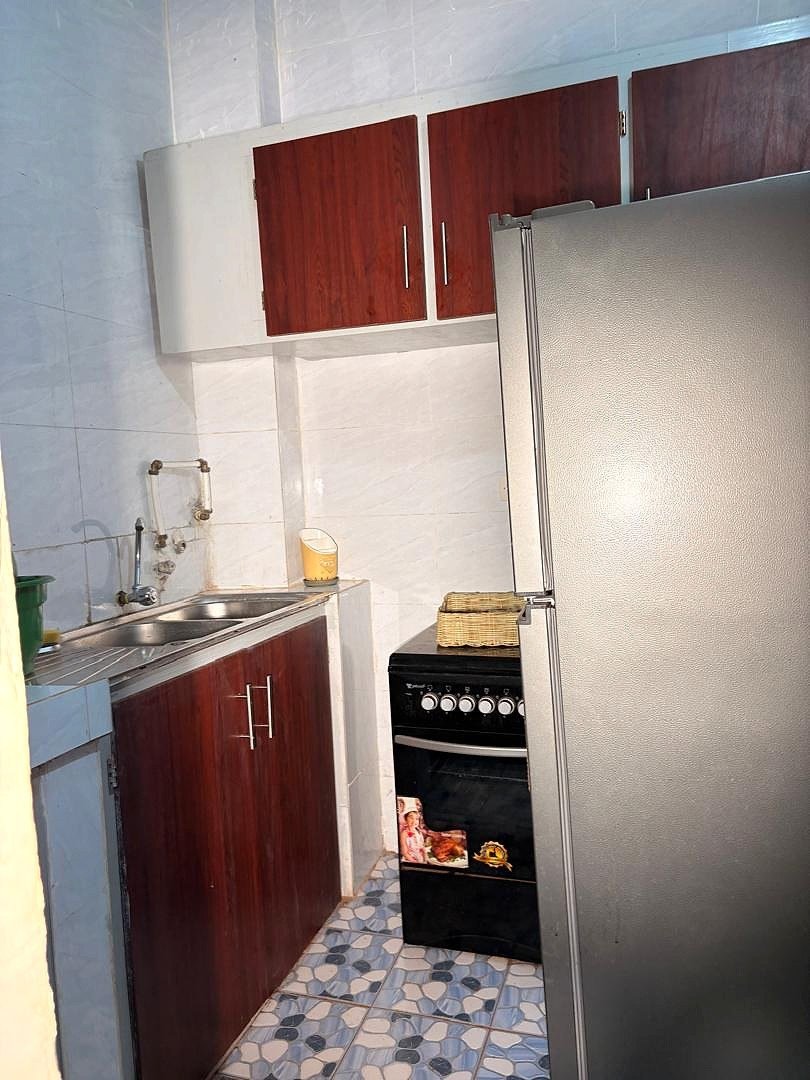 Cuisine aménagée avec rangements, évier, cuisinière et réfrigérateur